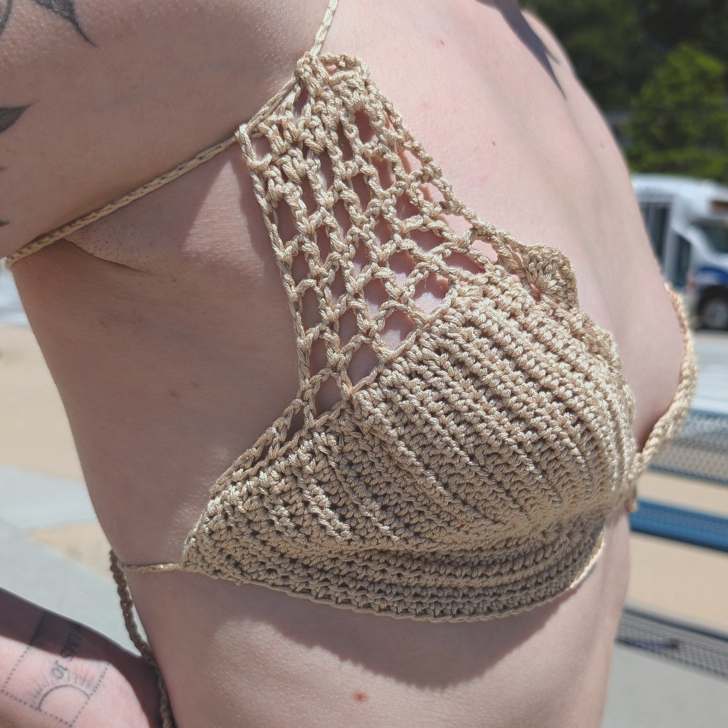 Person wearing a cream crochet bikini top outdoors on a sunny day.