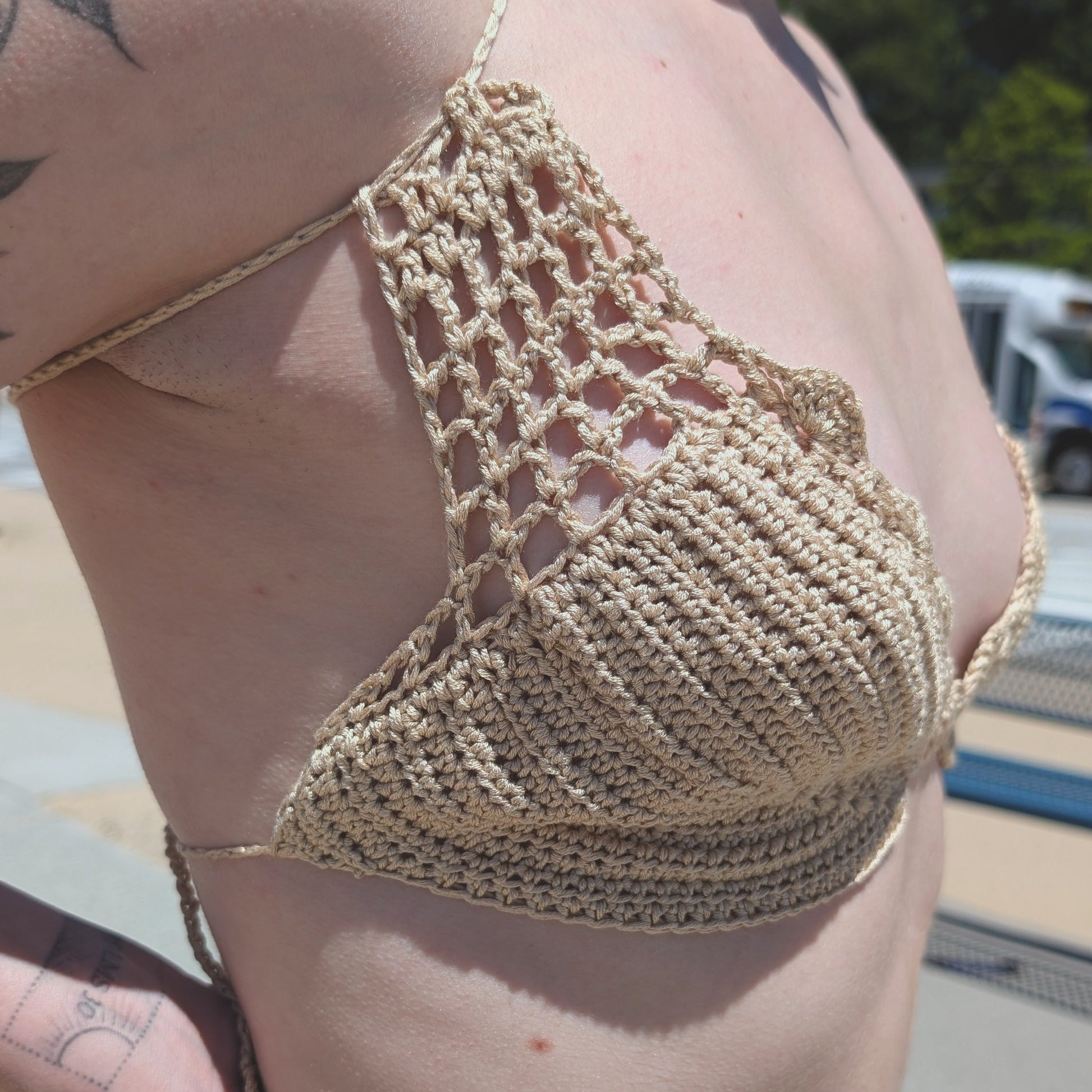Person wearing a cream crochet bikini top outdoors on a sunny day.