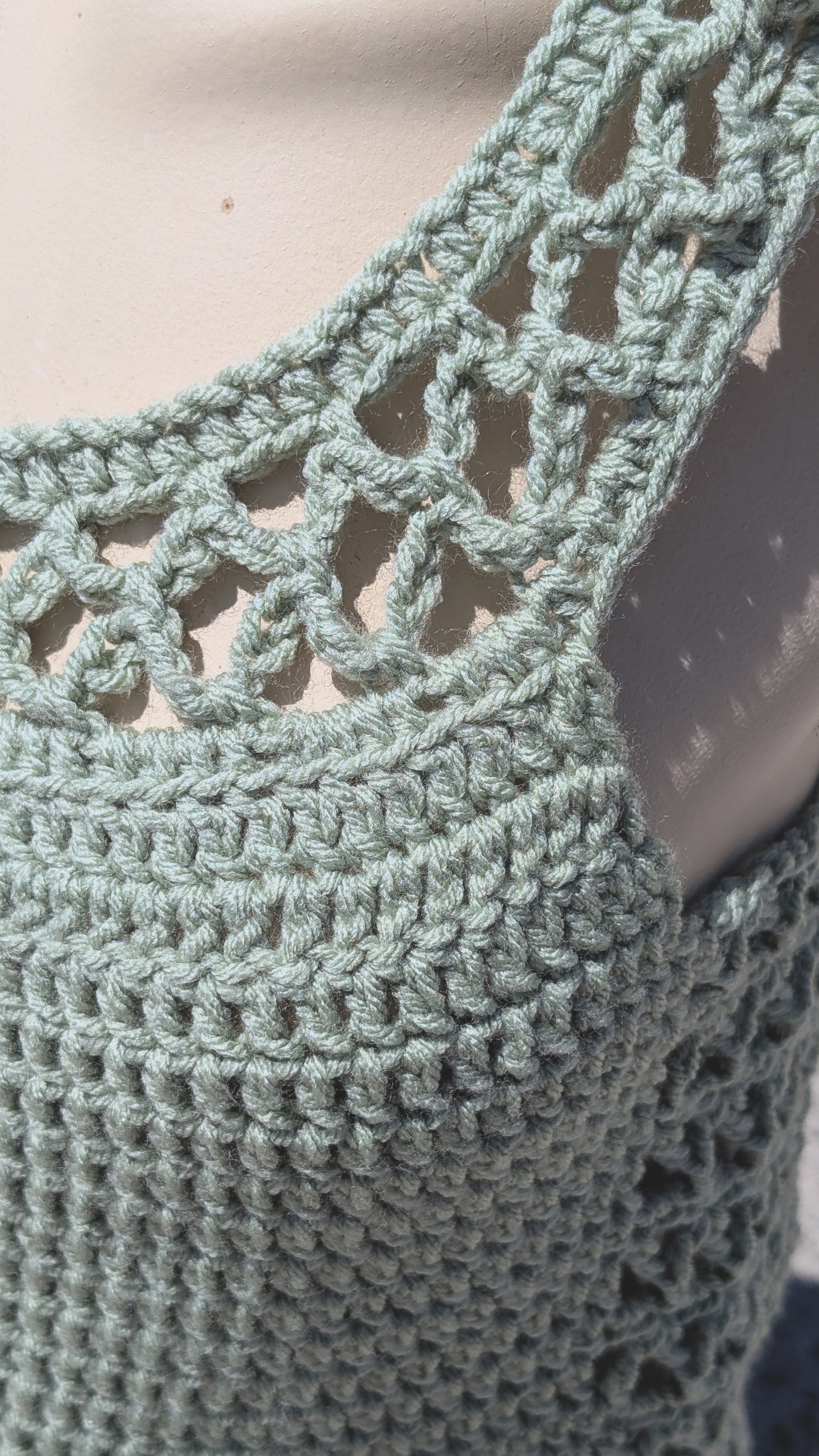 Close-up of a green crochet garment with intricate patterns.