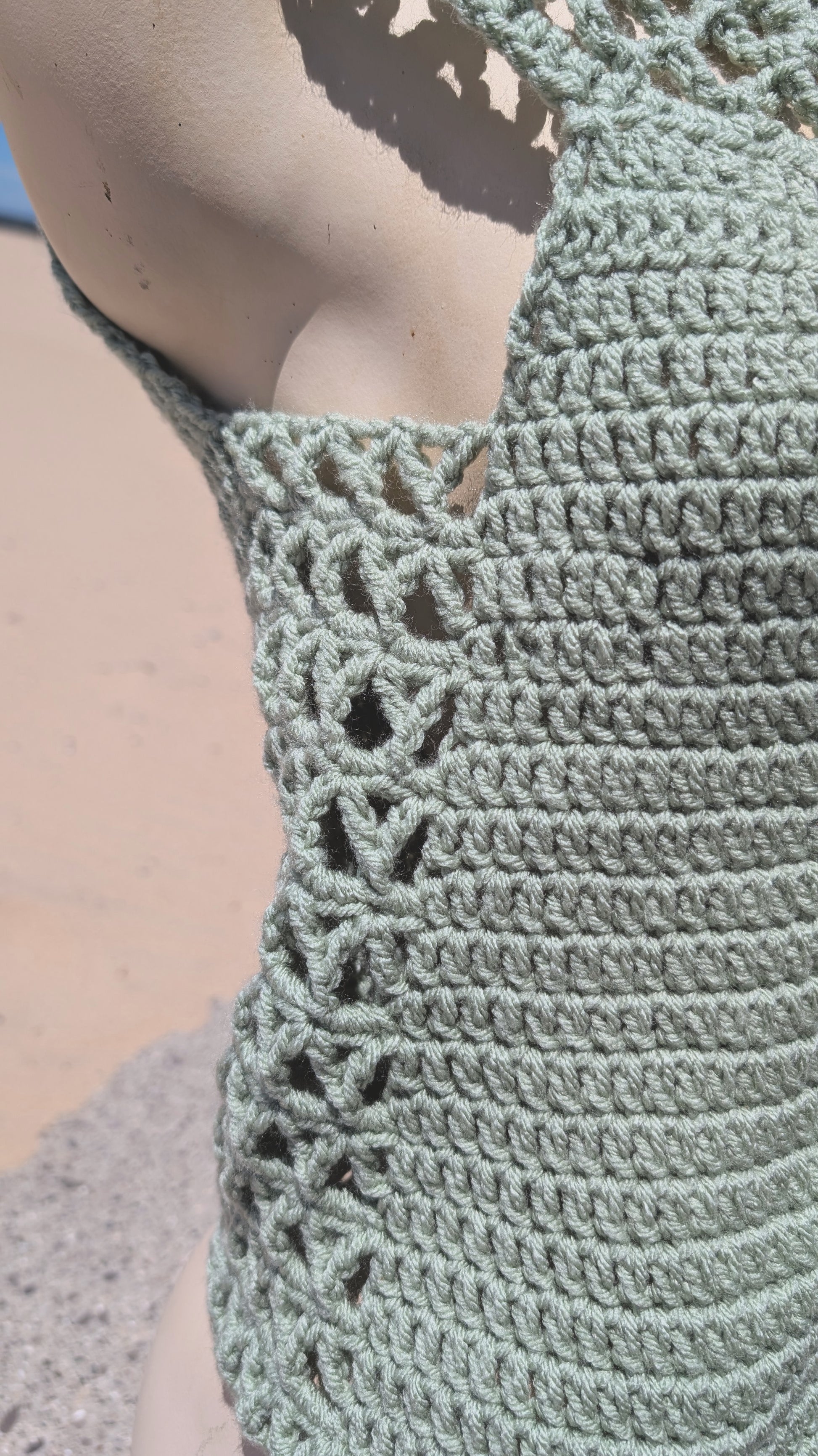 Close-up of a green crochet top with intricate patterns.