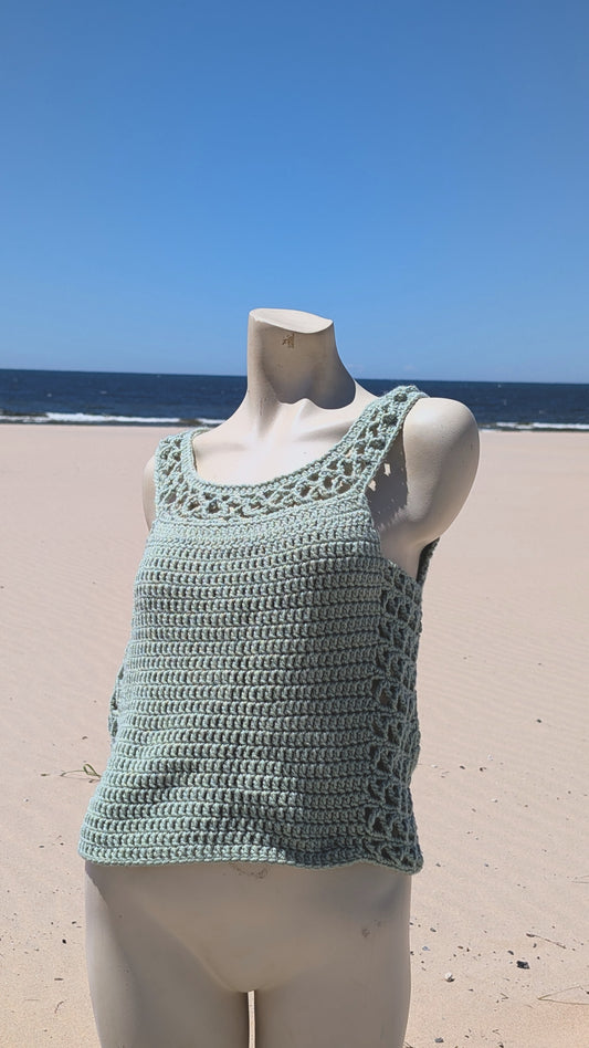 Crocheted tank top on a mannequin against a beach background
