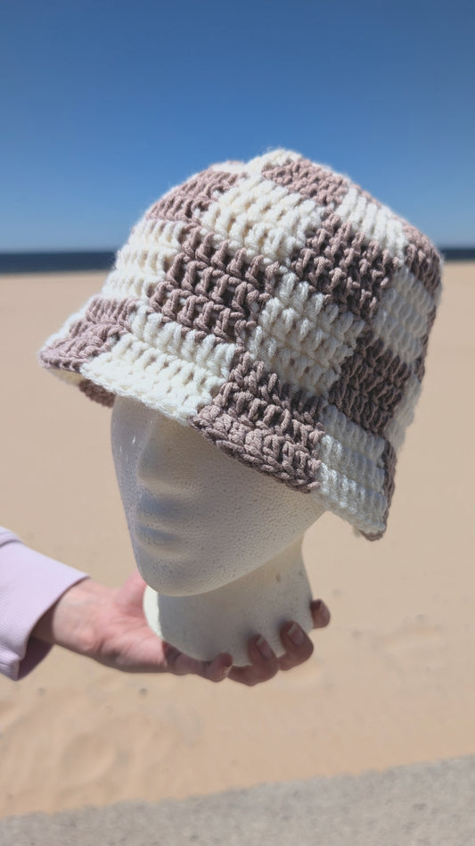 Crocheted hat on a mannequin head against a beach background