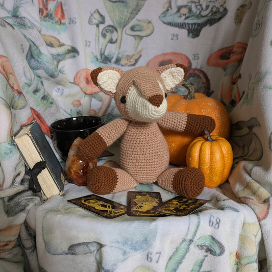 Handmade crochet fox plush in rust, cream, and sunset orange on a warm autumn backdrop