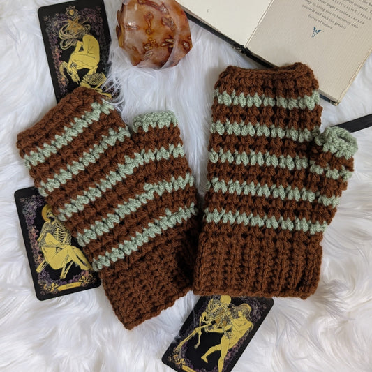 Handmade moss and brown crochet fingerless mitts with a faux-cable texture on a warm autumn backdrop