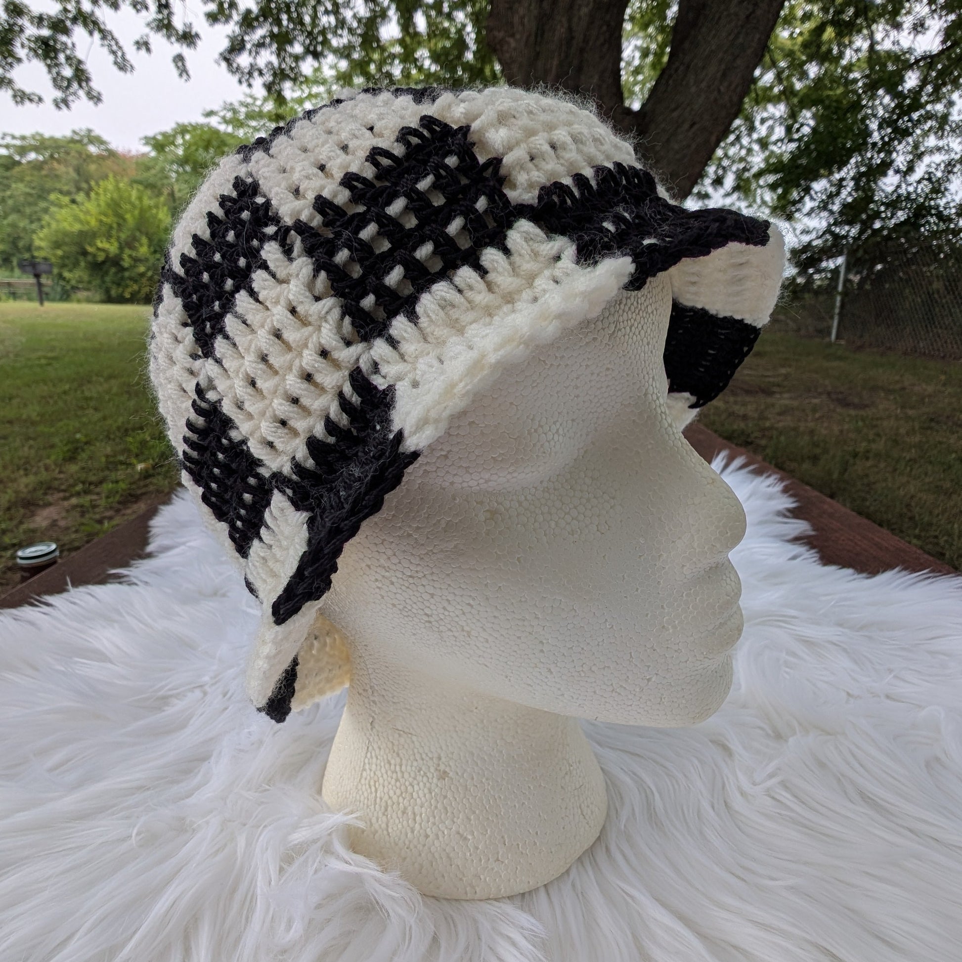 Handmade black and cream checkerboard crochet bucket hat on a mannequin