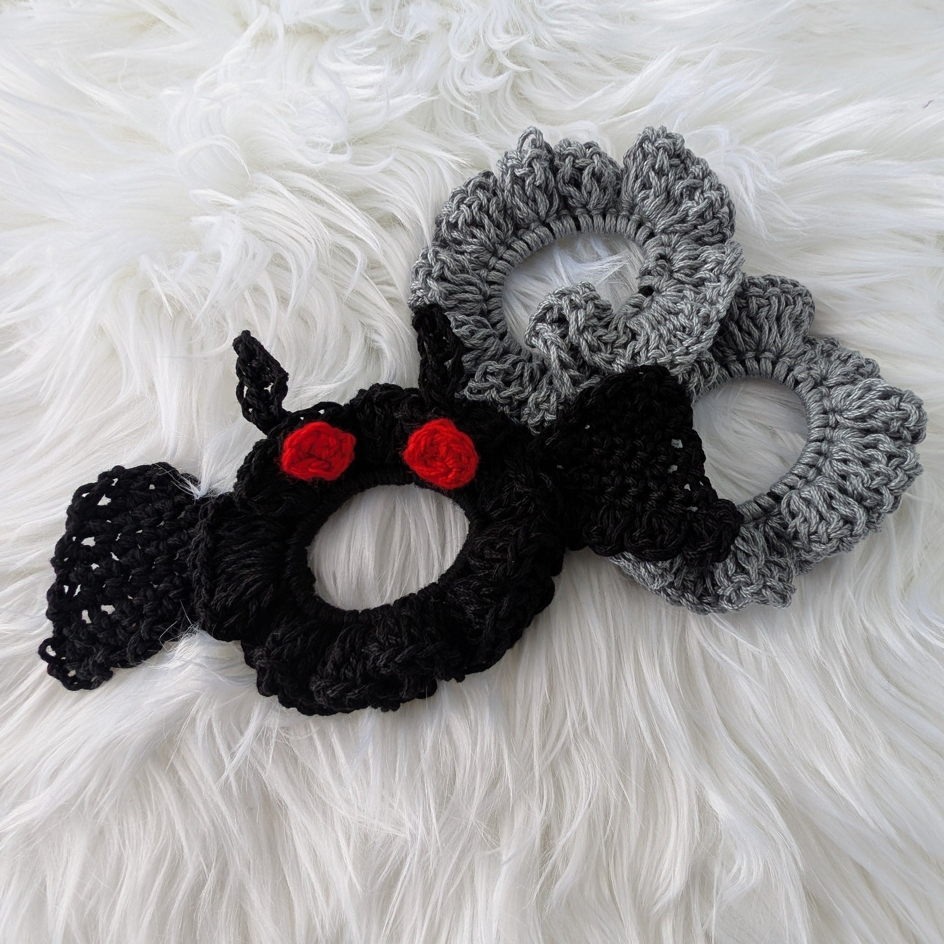 Set of three handmade crochet scrunchies — one black Mothman with red eyes and wings, two silver